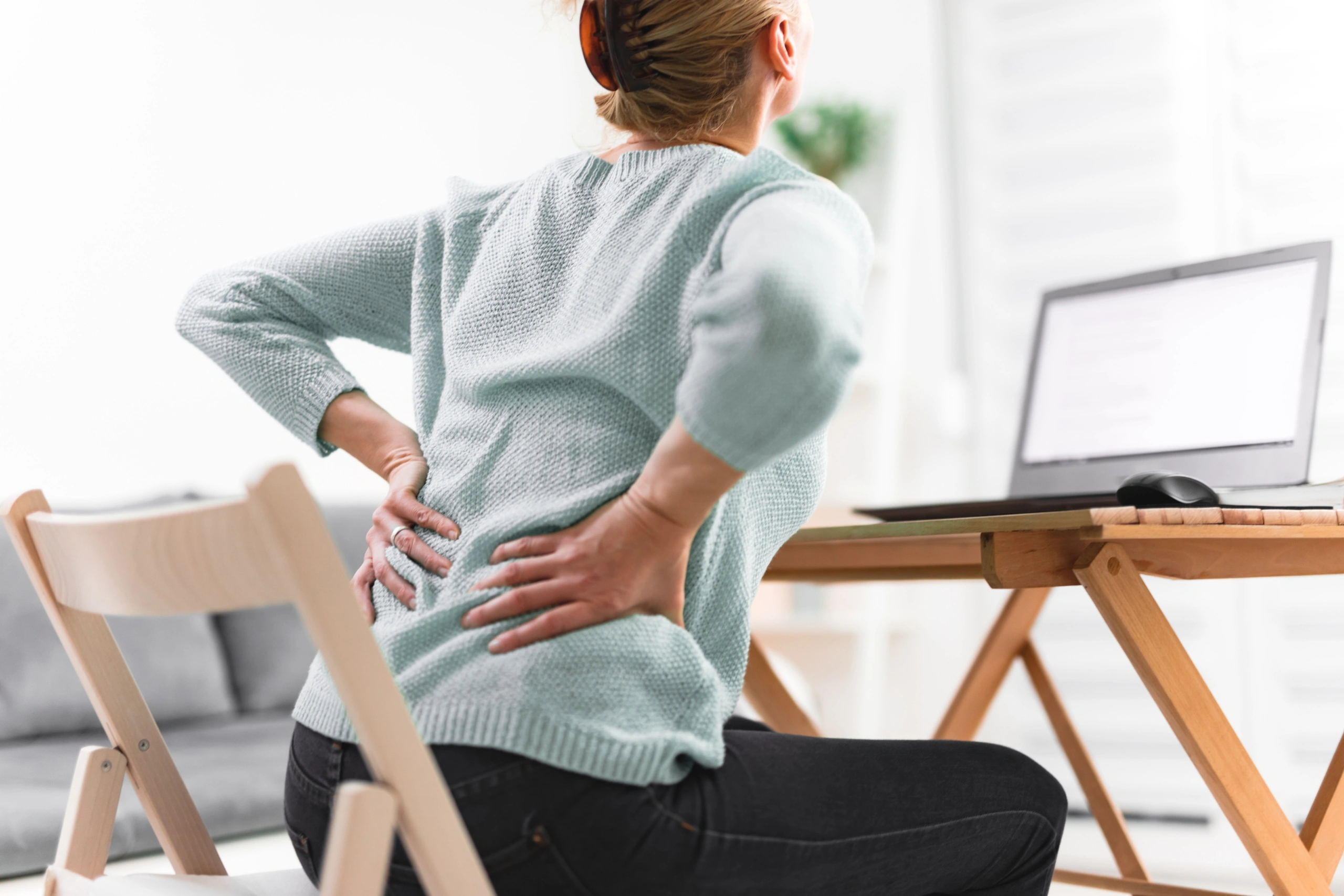 Woman working on a laptop and having back, hip, spine pain. (1)